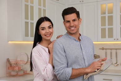 Photo of Happy couple with clean dishes in kitchen