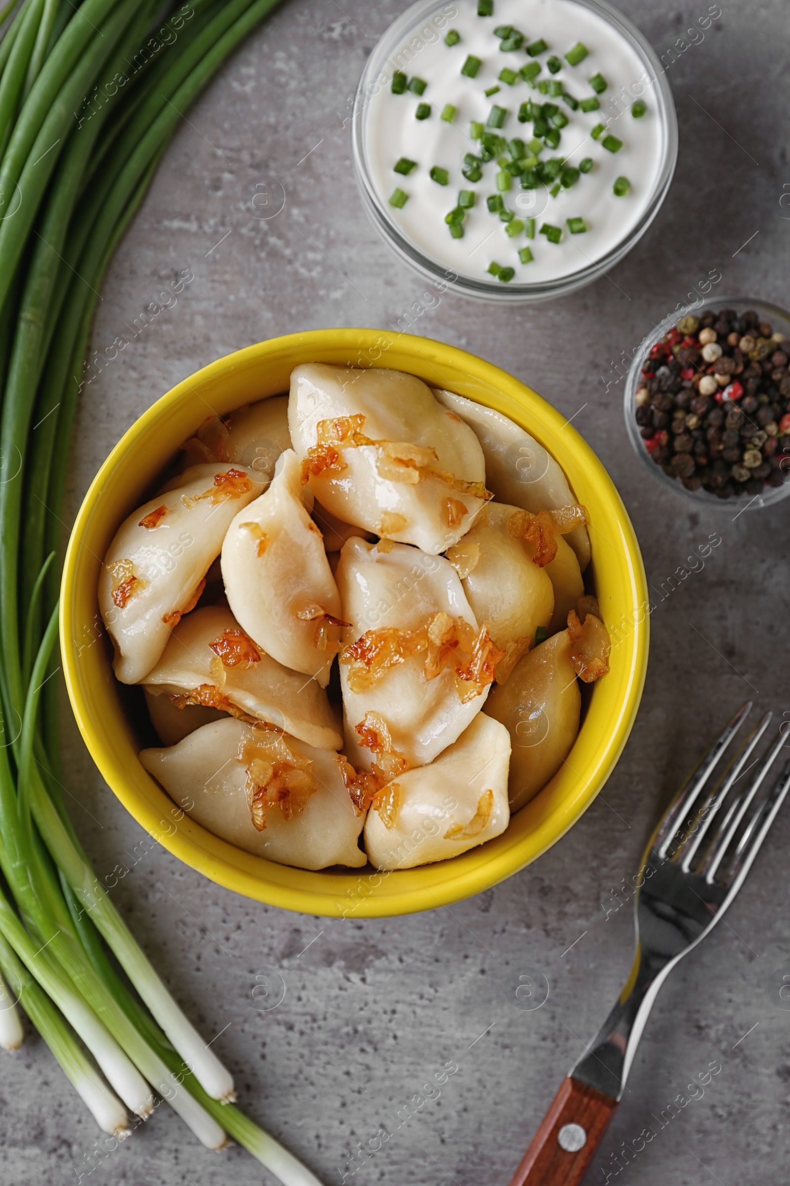 Photo of Delicious cooked dumplings with fried onion on grey table, flat lay