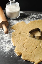 Photo of Making shortcrust pastry. Raw dough, flour, cookie cutter and rolling pin on grey table