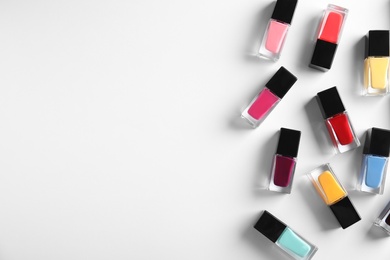 Photo of Bottles of bright nail polish on white background, top view