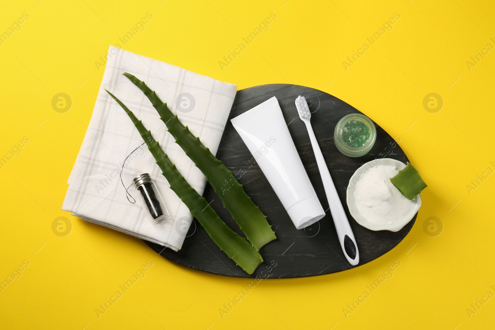 Photo of Aloe vera toothpaste in blank tube, brush, green leaves and care products on yellow background, top view. Space for text