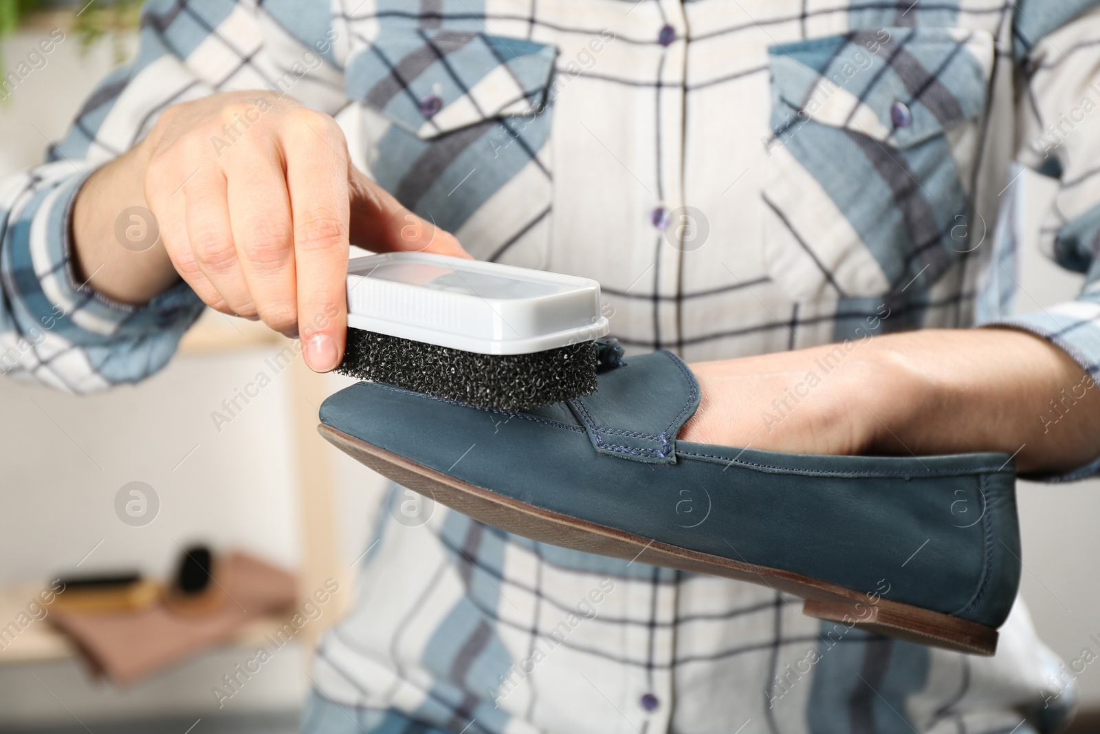 Photo of Woman taking care of stylish shoe indoors, closeup