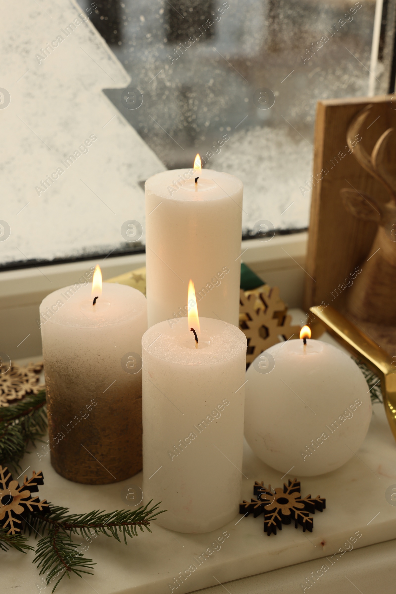 Photo of Beautiful burning candles with Christmas decor on windowsill indoors