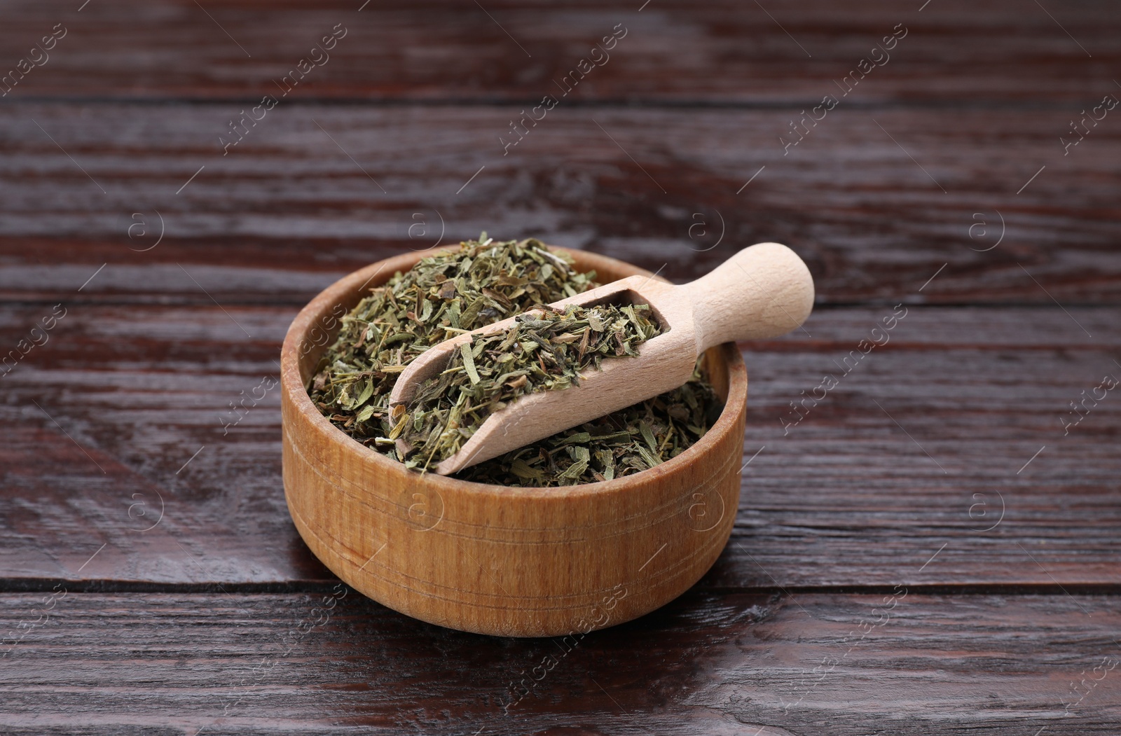 Photo of Bowl of dry tarragon and scoop on wooden table