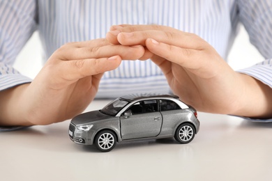 Female insurance agent covering toy car at table, closeup