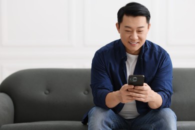 Portrait of smiling businessman with smartphone indoors. Space for text