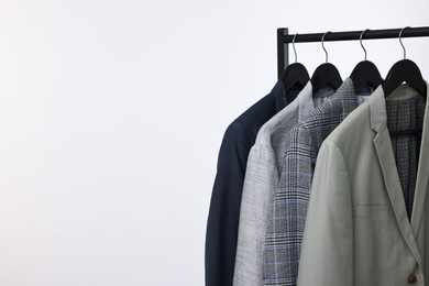 Dry-cleaning service. Many different clothes hanging on rack against white background, space for text