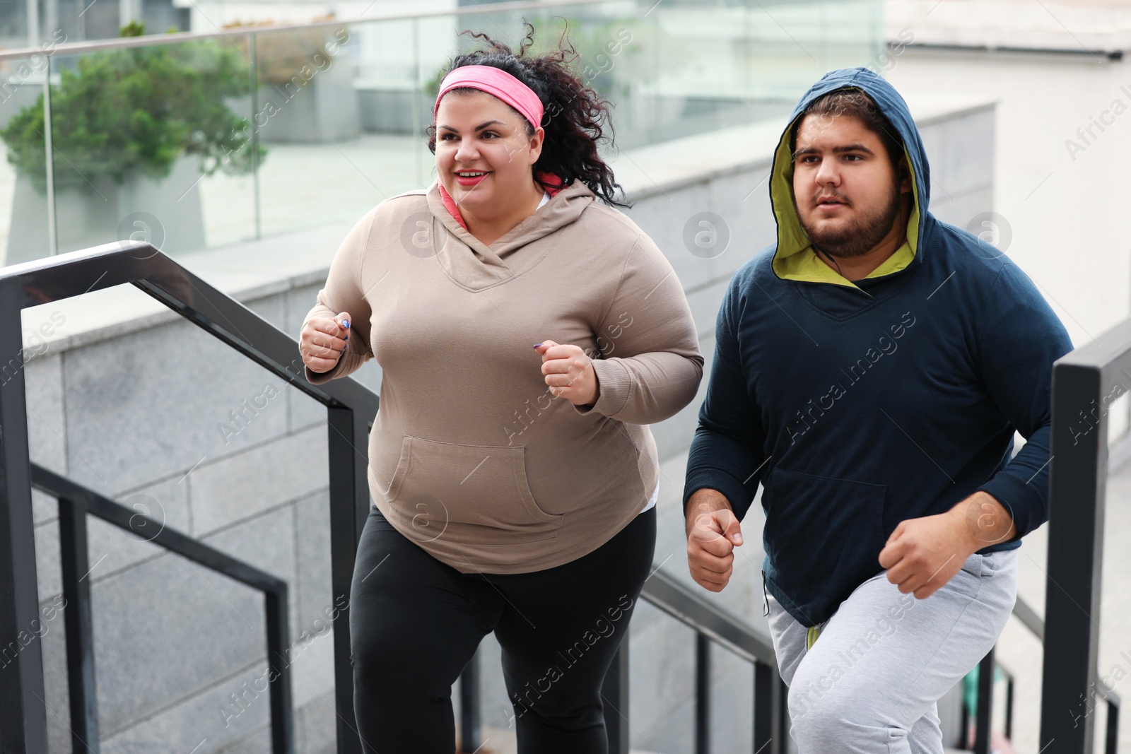 Photo of Overweight couple running up stairs together outdoors