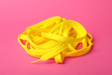 Photo of Yellow shoe lace on pink background. Stylish accessory