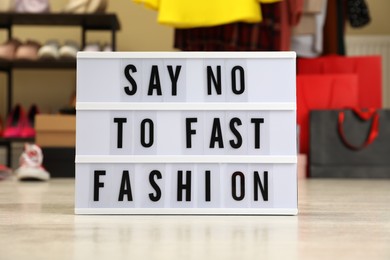 Photo of Lightbox with phrase SAY NO TO FAST FASHION on floor indoors