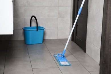 Photo of Mop and bucket on tiled floor in toilet