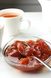 Photo of Quince jam in glass bowl served to tea on white table, closeup
