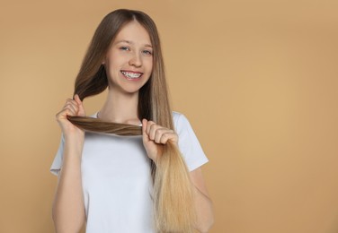 Photo of Teenage girl with strong healthy hair on beige background, space for text