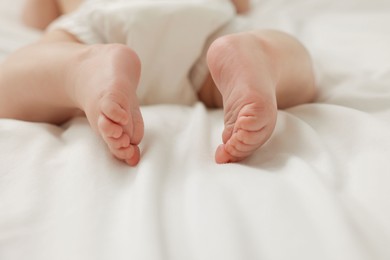 Little baby in diaper on white bed, closeup