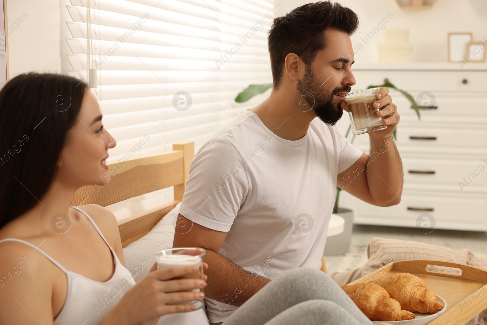 Photo of Happy couple having breakfast on bed at home