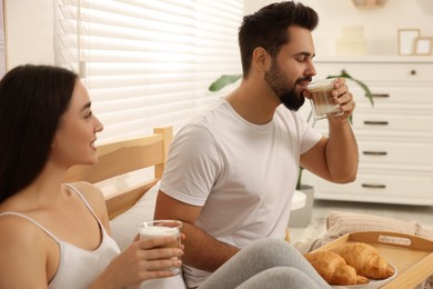 Happy couple having breakfast on bed at home