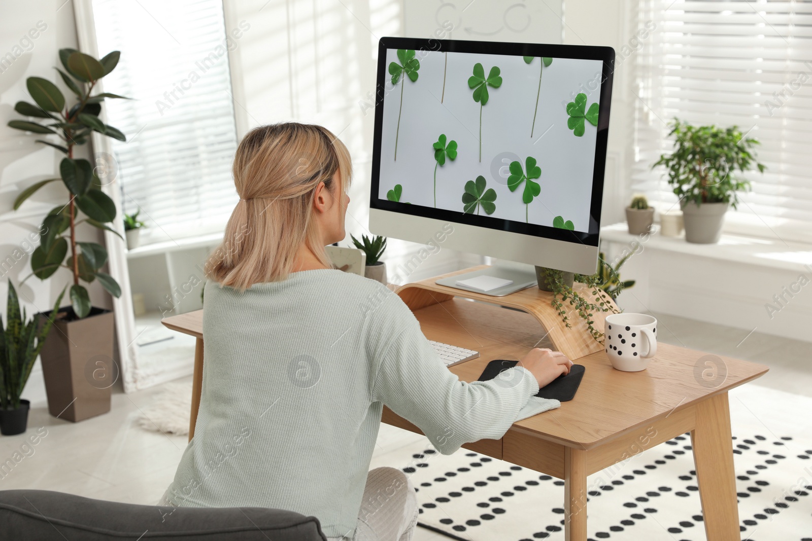 Photo of Woman working at table in light room, back view. Home office