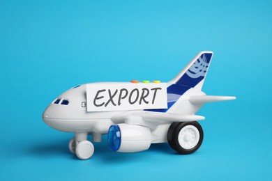Photo of Card with word EXPORT and toy plane on light blue background
