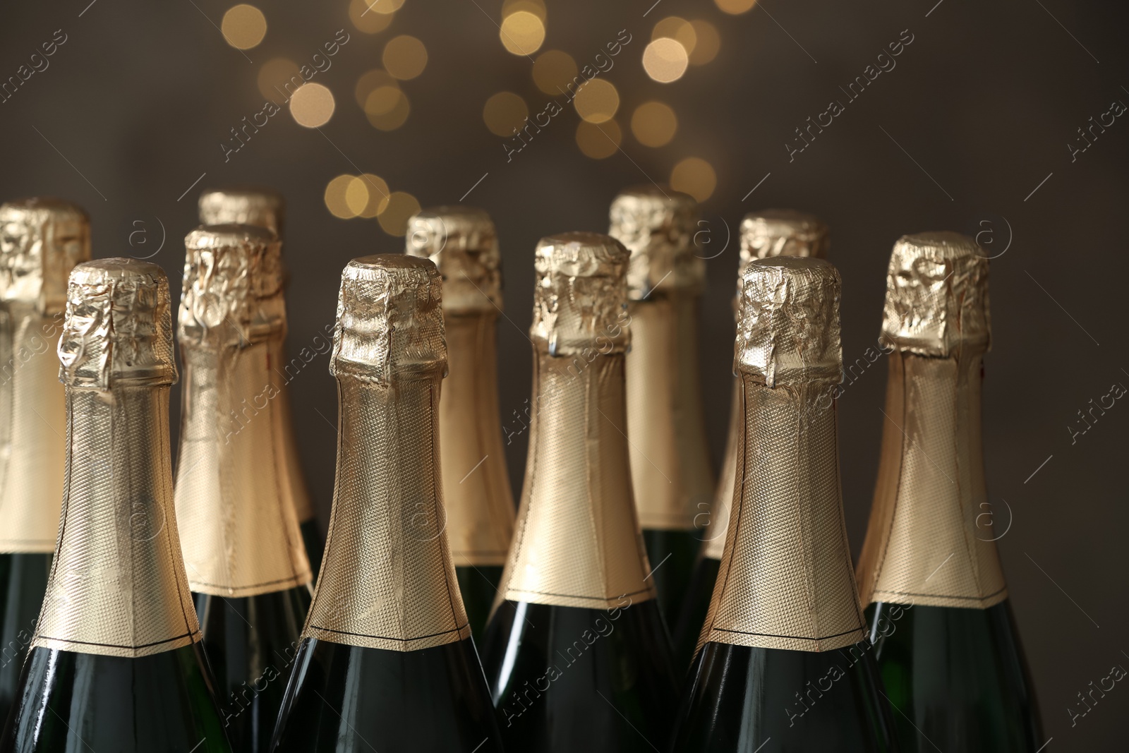 Photo of Many bottles of champagne on blurred background, closeup