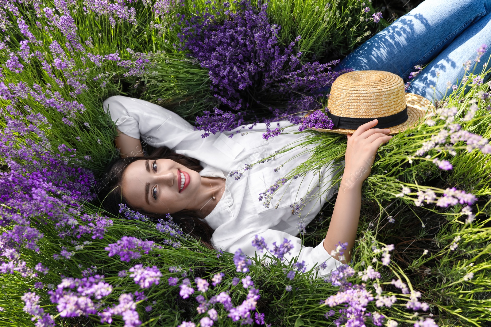 Photo of Young woman lying in lavender field on summer day