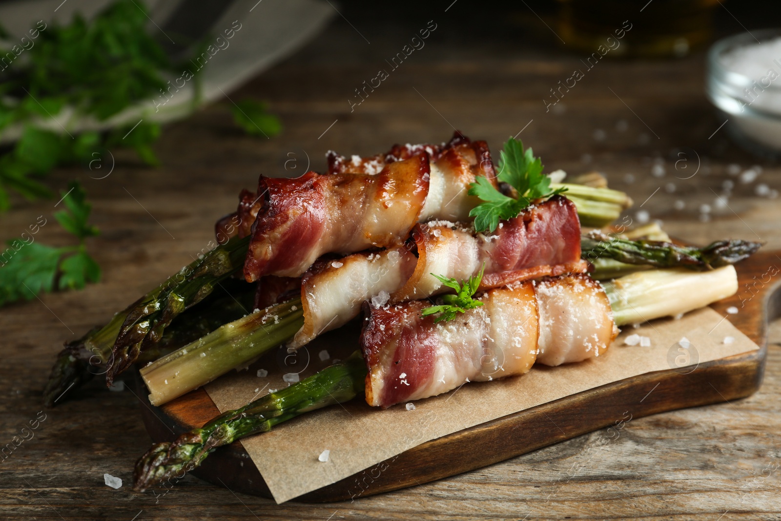 Photo of Oven baked asparagus wrapped with bacon on wooden table