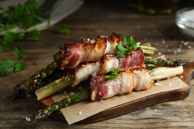 Oven baked asparagus wrapped with bacon on wooden table