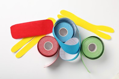 Photo of Bright kinesio tape rolls and pieces on white background, flat lay