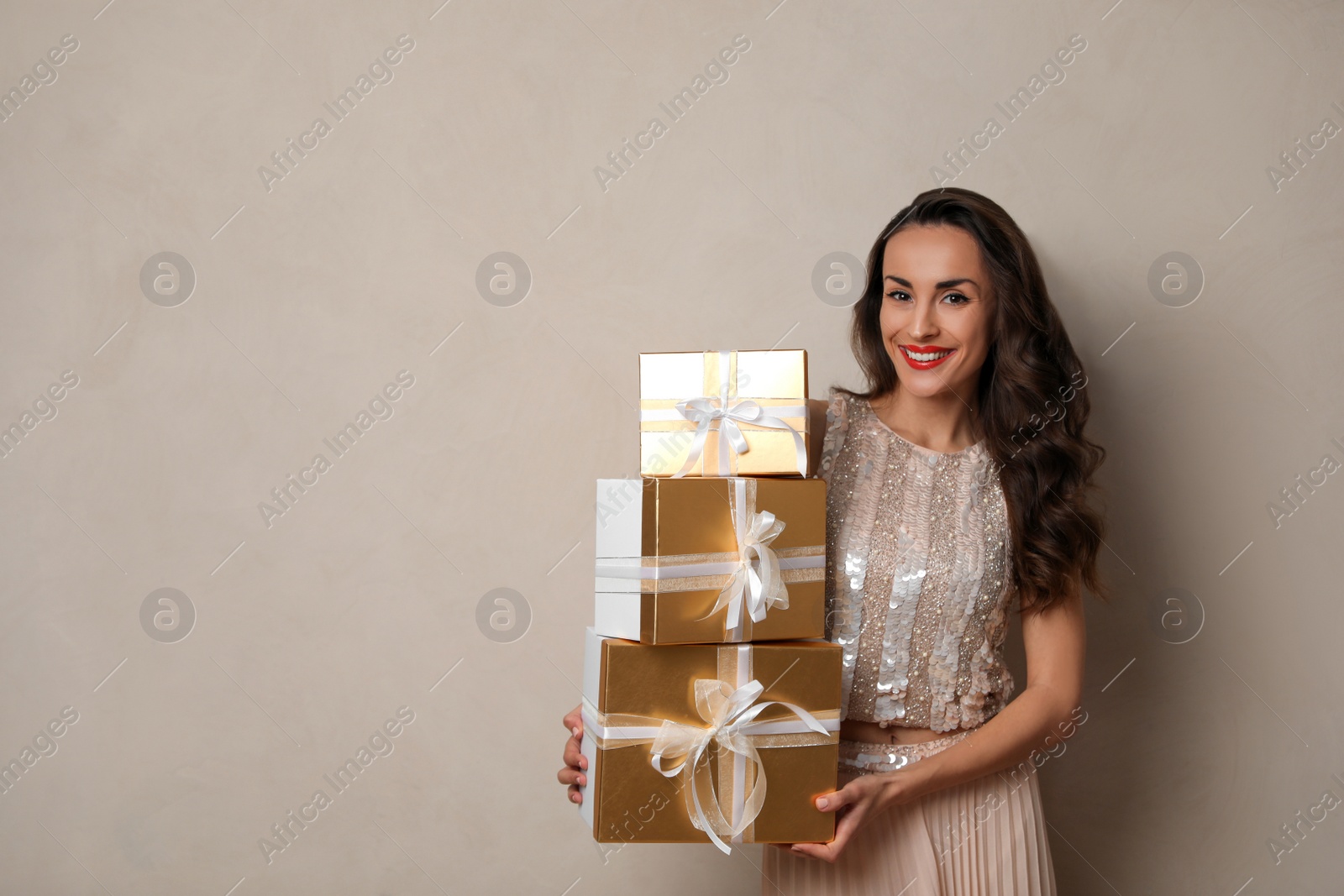 Photo of Beautiful woman with gift boxes on beige background, space for text. Christmas celebration