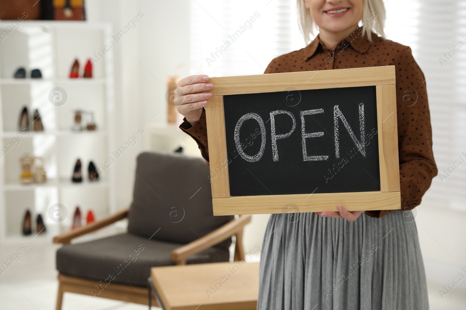 Photo of Female business owner holding OPEN sign in boutique, closeup