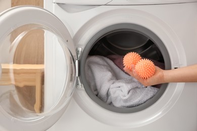 Woman putting dryer balls into washing machine, closeup