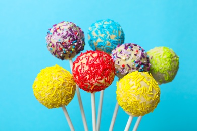 Yummy bright cake pops on color background