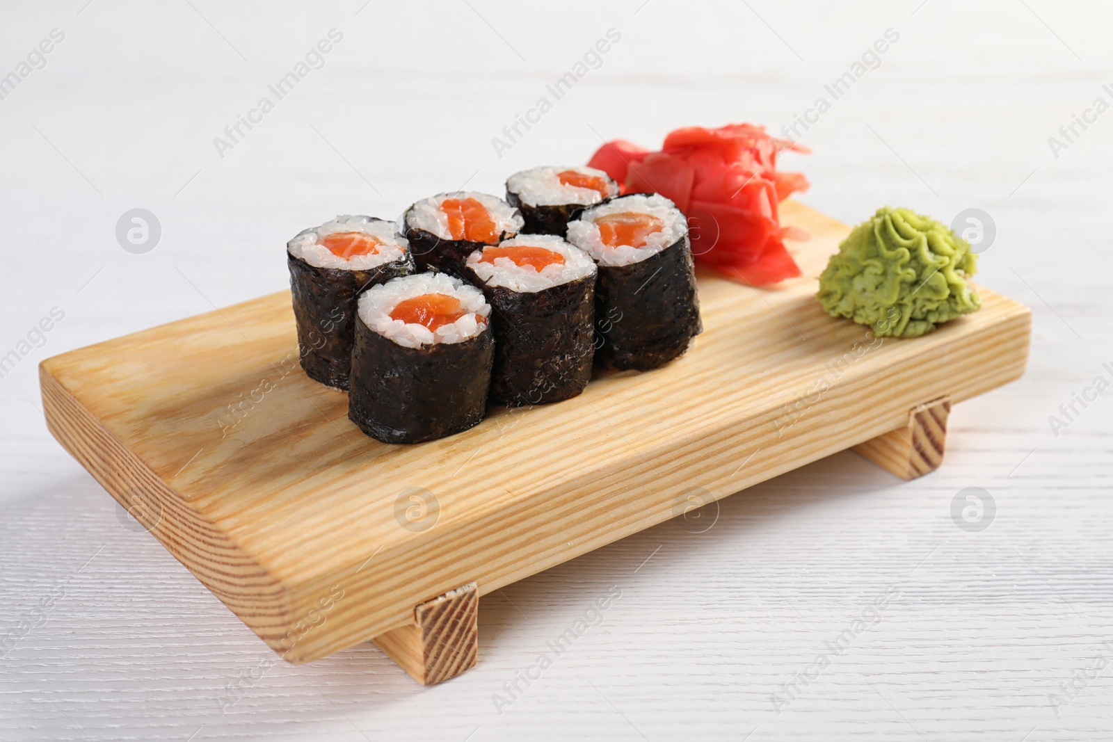 Photo of Serving board with tasty sushi rolls on white table. Food delivery