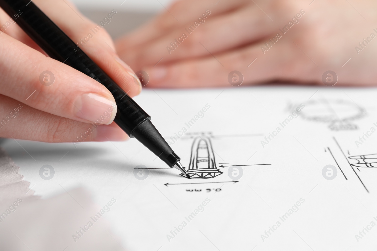 Photo of Jeweler drawing sketch of elegant ring on paper, closeup