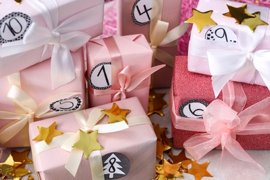 Photo of Gifts for Christmas advent calendar and confetti on light table, closeup