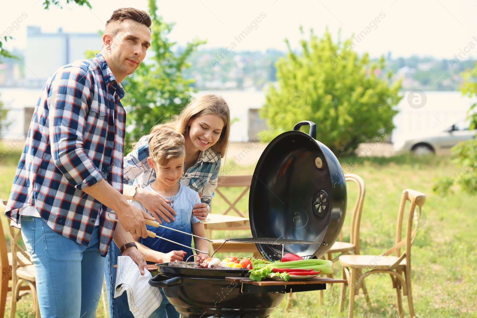 Photo of Happy family having barbecue with modern grill outdoors