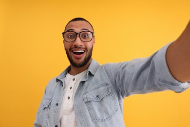 Photo of Smiling young man taking selfie on yellow background