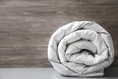 Photo of Soft rolled blanket on light grey table. Space for text