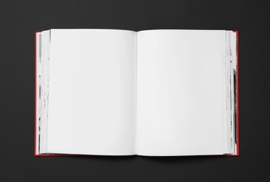 Photo of Open book with blank pages on black background, top view. Space for text