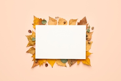 Flat lay composition with autumn leaves and blank card on light background, space for text