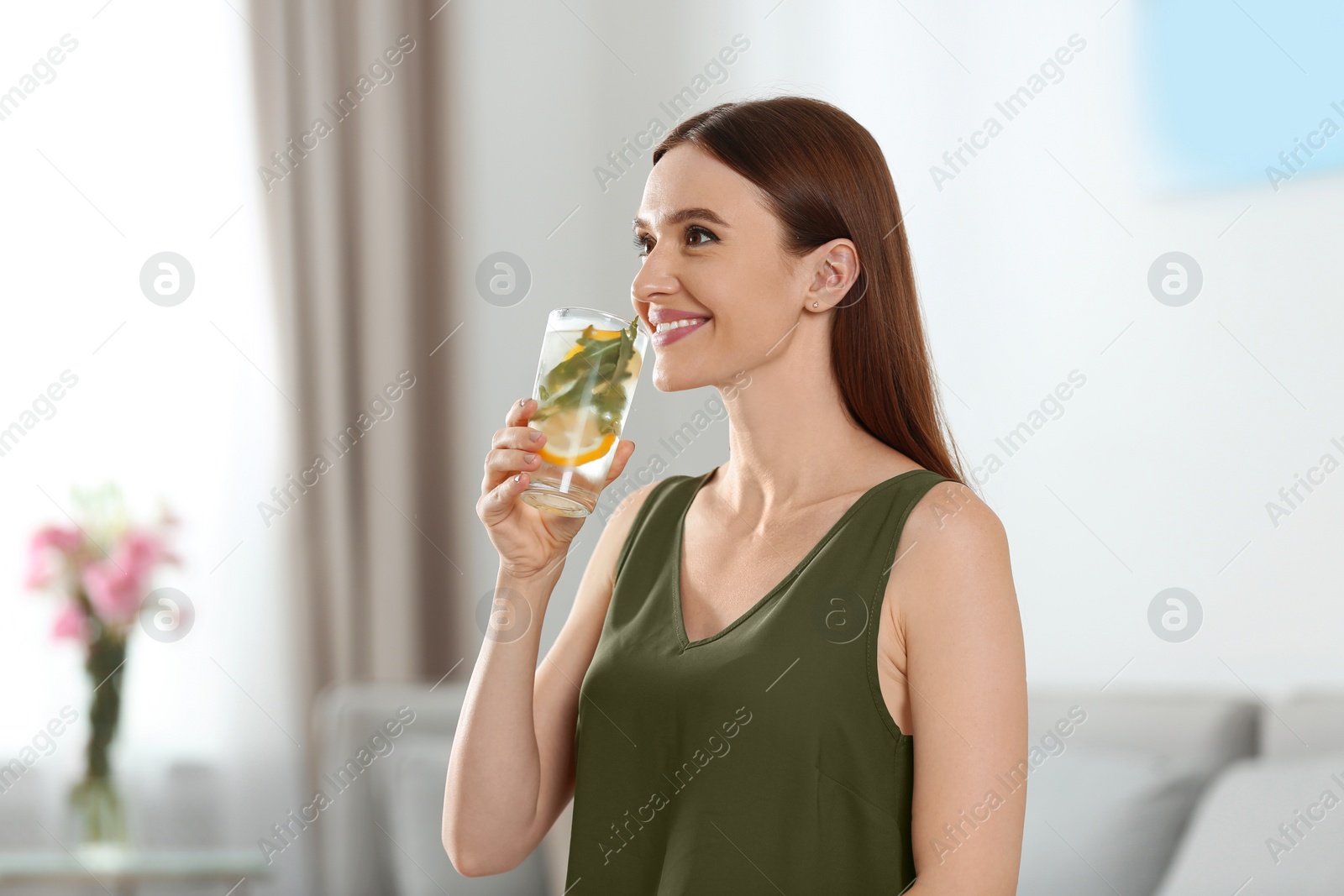 Photo of Young woman with lemonade at home. Refreshing drink