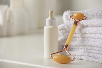 Photo of Natural face roller, towels and serum on white table, closeup. Space for text