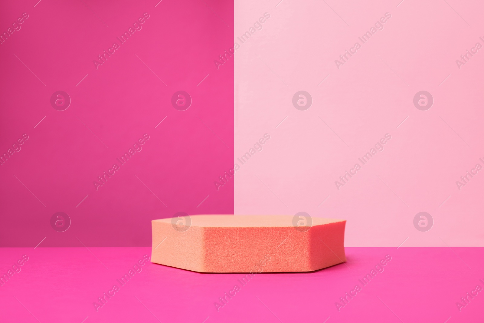 Photo of Orange geometric stand on pink background. Stylish presentation for product