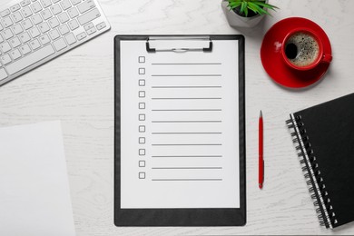 Photo of Clipboard with checkboxes, cup of coffee, plant and computer keyboard on white wooden table, flat lay. Checklist