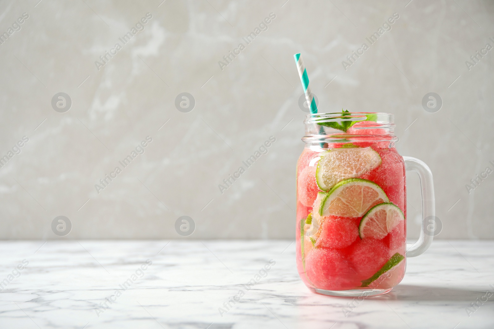 Photo of Tasty refreshing watermelon drink on marble table against grey background. Space for text