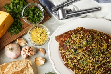 Photo of Tasty homemade garlic bread with cheese and herbs on grey table, flat lay