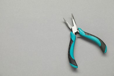 Photo of Bent nose pliers on grey background, top view. Space for text