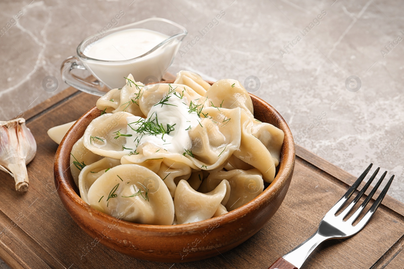 Photo of Tasty dumplings with sour cream in bowl on table