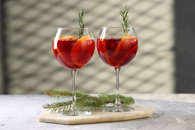 Photo of Christmas Sangria cocktail in glasses and fir tree branch on grey textured table