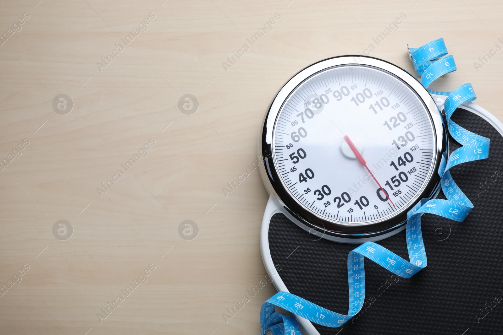 Photo of Bathroom scale, measuring tape and space for text on wooden floor, top view. Weight loss concept