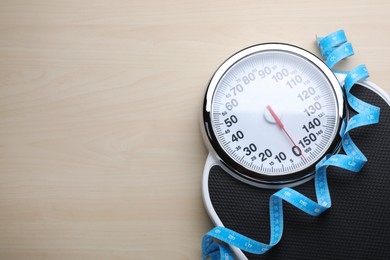 Photo of Bathroom scale, measuring tape and space for text on wooden floor, top view. Weight loss concept